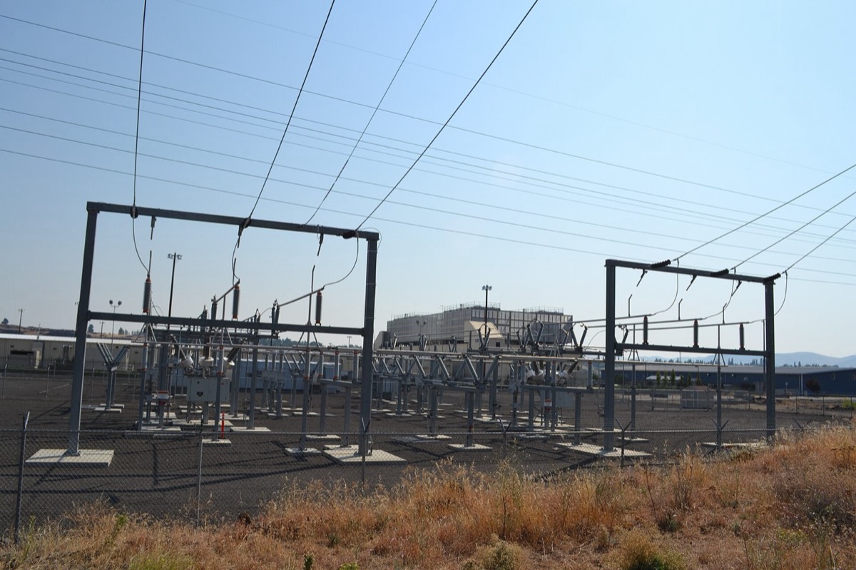 High-voltage electrical substation with a data-center building behind it in The Dalles, Oregon